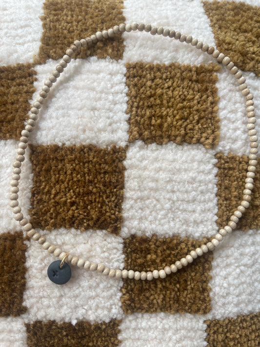 Collier perles de bois et croix gravée sur pampille ronde noire en céramique