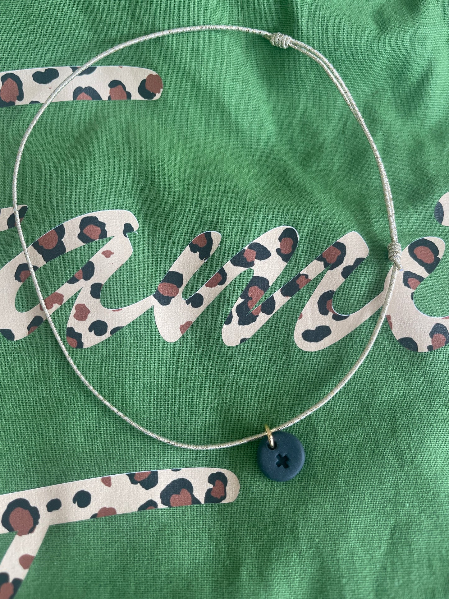 Collier élastique et céramique noire croix gravée sur une pampille ronde