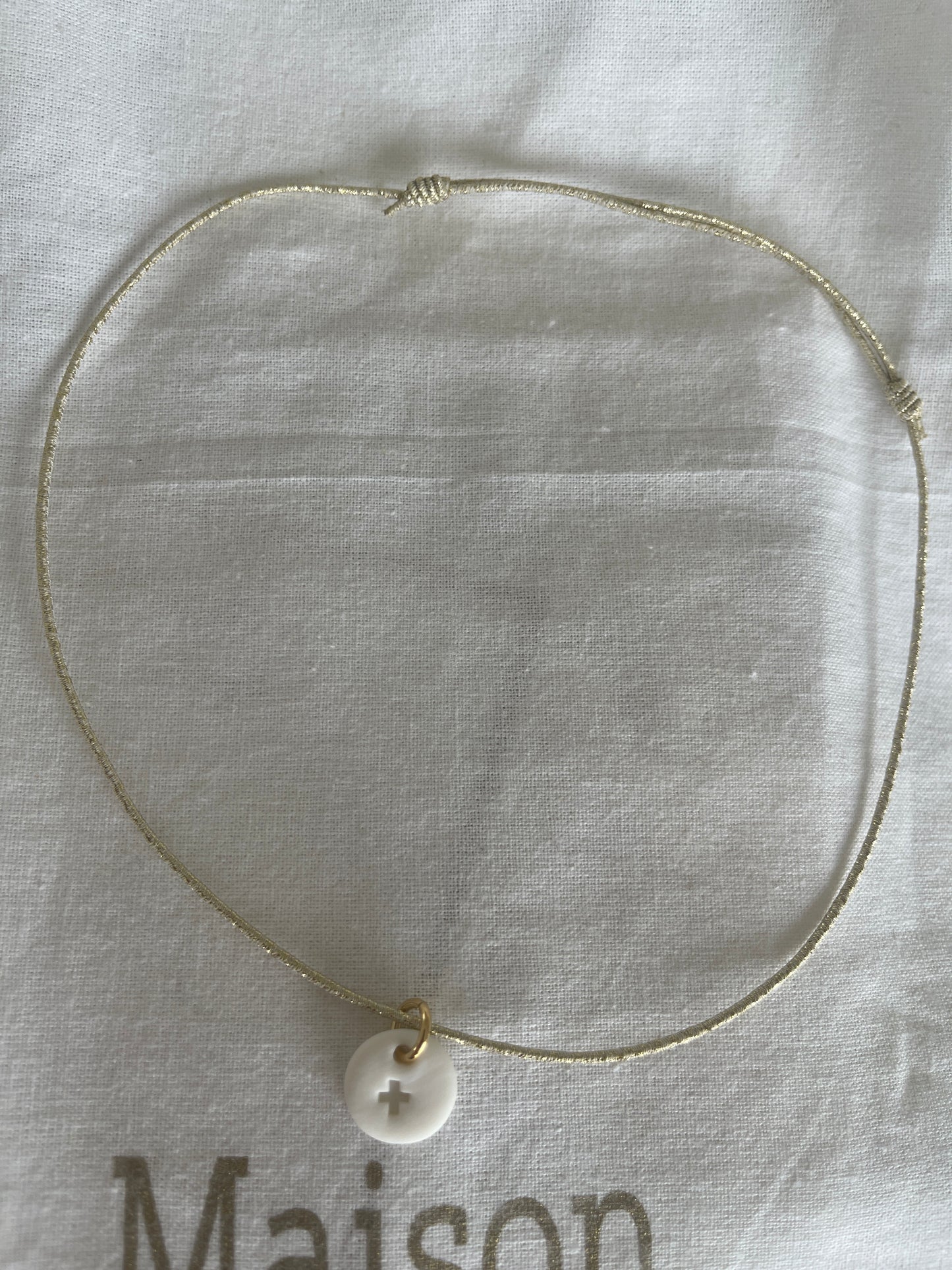 Collier élastique et céramique blanche croix gravée sur pampille ronde